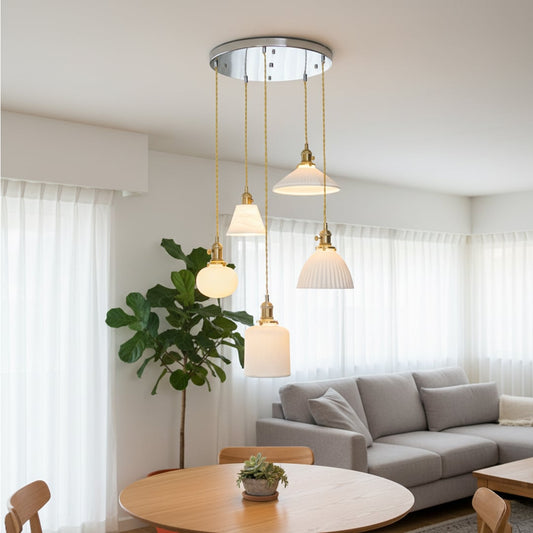 Elegant ceramic pendant cluster with mixed white textured shades and gold fittings hanging from a silver ceiling plate creating a refined room look.