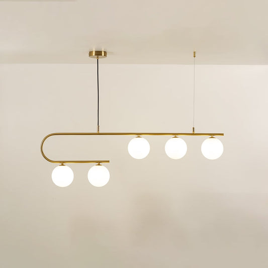 Gold asymmetrical ceiling light with curved arm and white globes in a front view against a plain background with lights on perfect for luxury lighting décor.