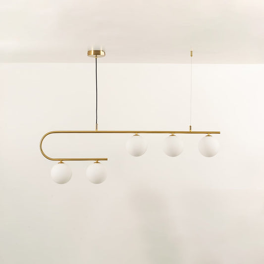 Gold asymmetrical ceiling light with white globes in a front view against a simple wall background with lights on perfect for luxury lighting décor.