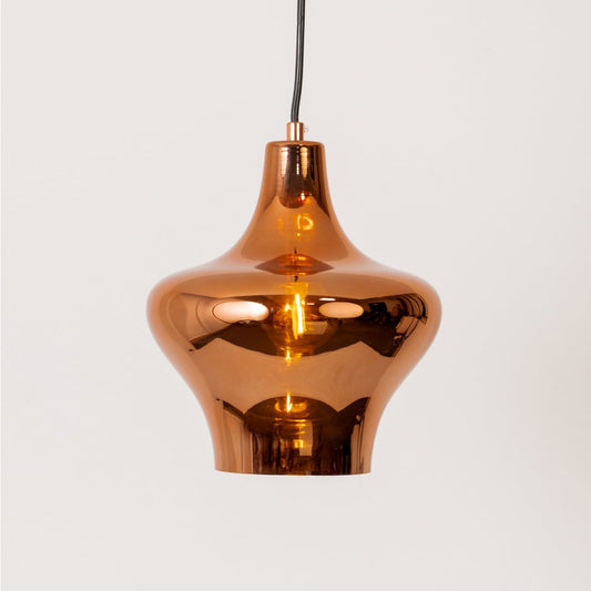 Copper metal pendant light glowing softly on a clean white background showcasing its smooth curved polished form.