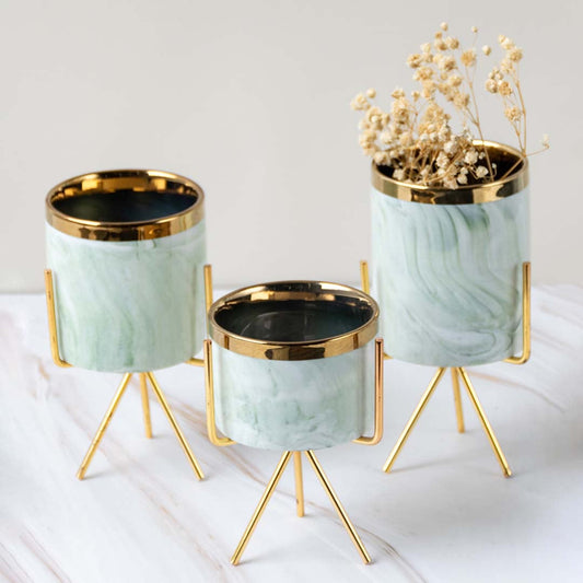 Small marble-textured planter with gold stand styled on a clean marble surface adding a chic modern accent to the lifestyle setting.