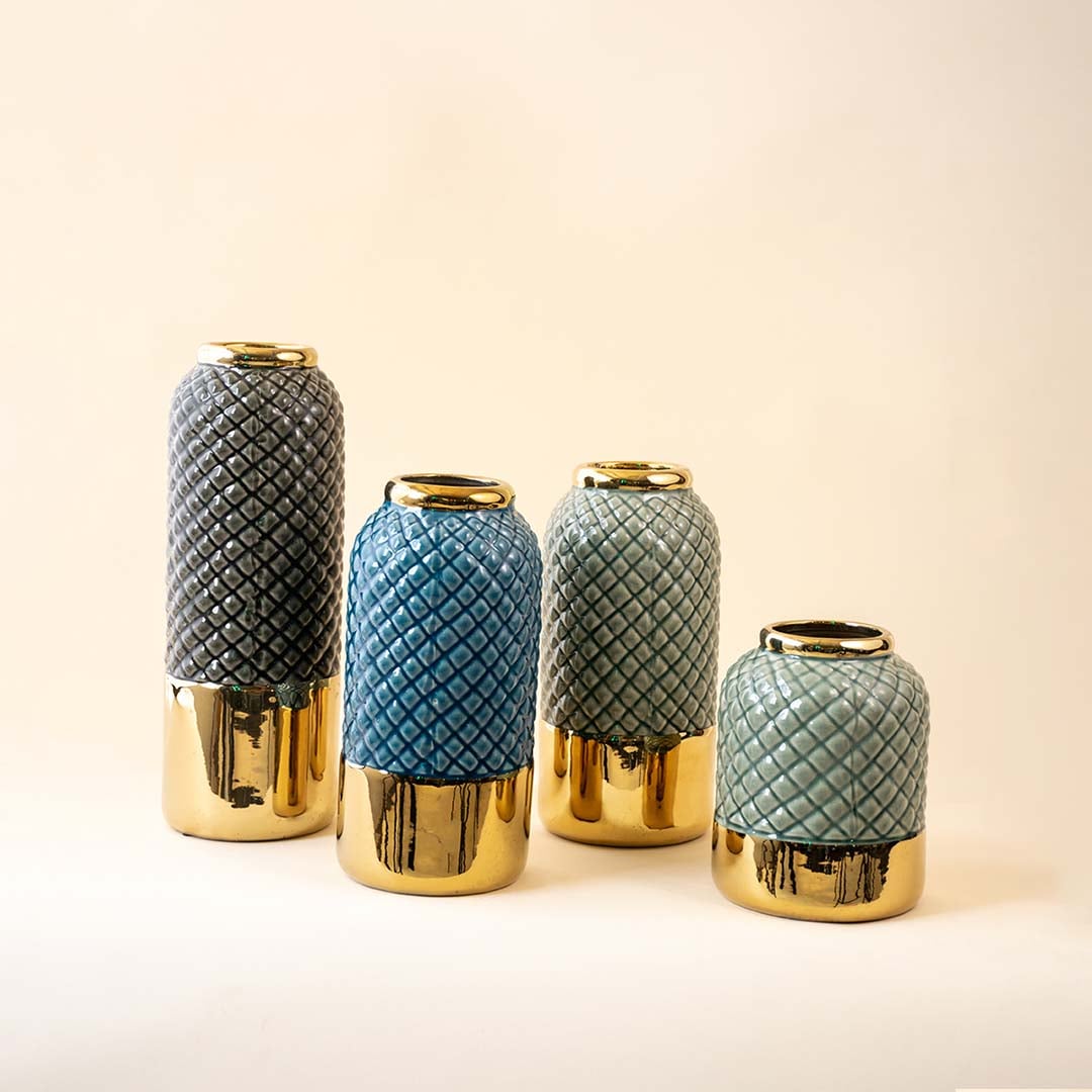 A collection of ceramic vases in grey blue and light blue tones with gold bases arranged together on a neutral background creating a cohesive decor display.