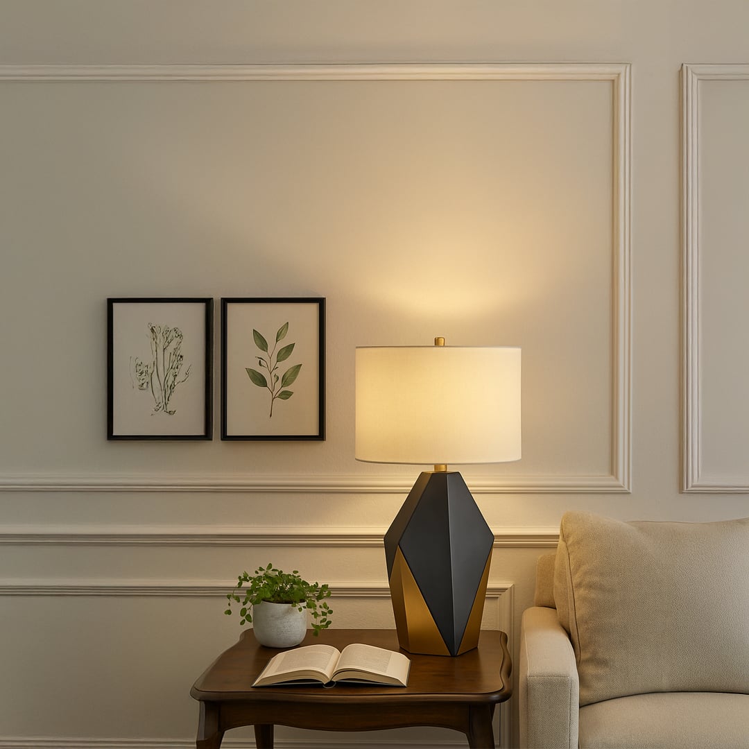 Black and gold geometric table lamp with a warm white drum shade placed on a wooden side table creating cozy ambient lighting in an elegant modern living room.