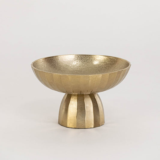 Gold pedestal bowl photographed on a plain white background highlighting its shape and metallic finish