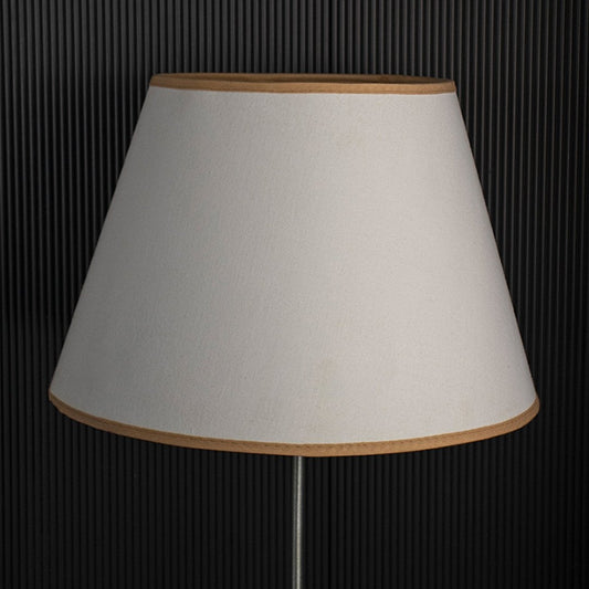 A classic tapered lampshade shown with light off black background highlighting its smooth beige fabric shape and clean stitched edges in a simple minimal style.