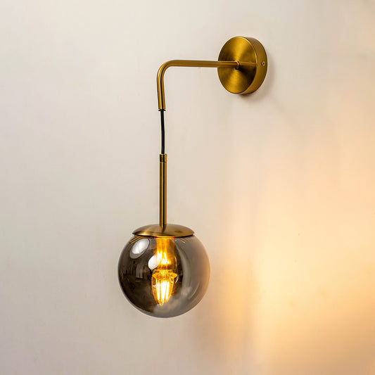 Stylish hanging glass globe wall light with gold metal arm mounted on warm neutral wall background perfect for modern luxury interior decor.