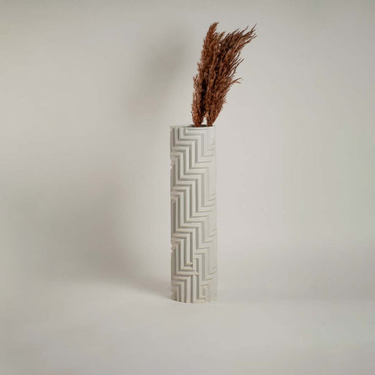 White ceramic vase with geometric detailing against a clean white backdrop emphasizing its refined craftsmanship.