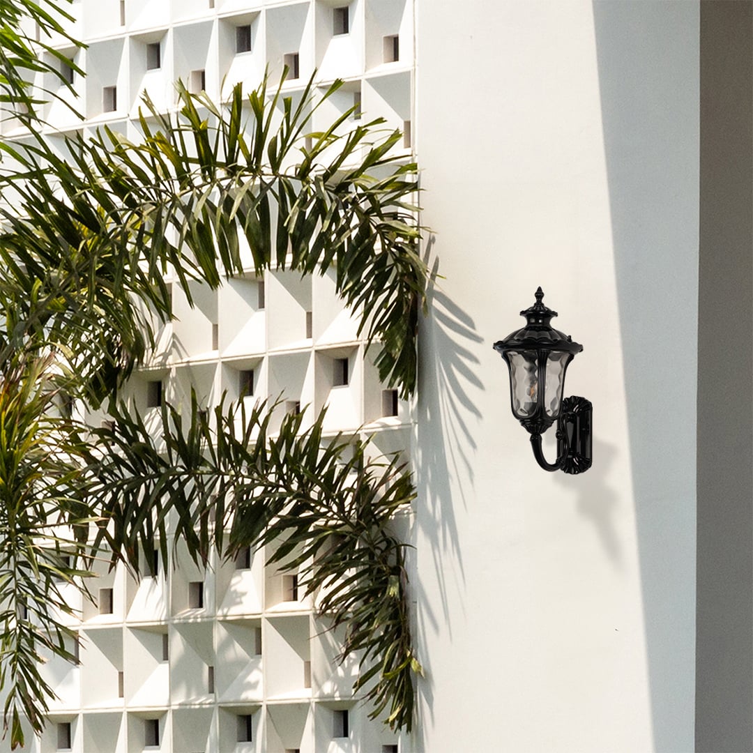 Stylish black outdoor wall lantern placed in an outdoor setting adding warm ambient light for porch pathway and garden decor.