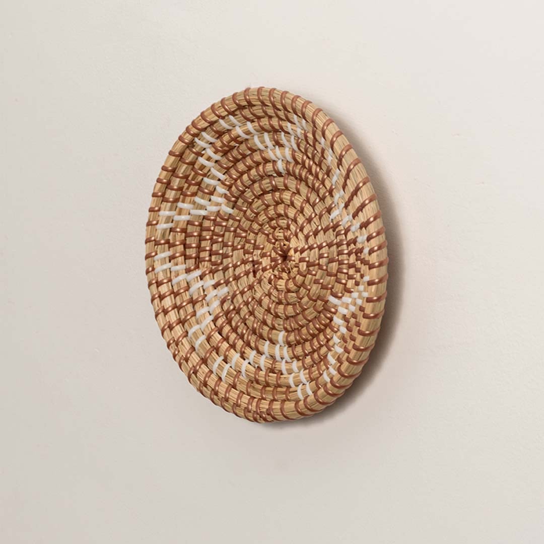 Side profile of the flat woven wall basket showing the natural texture and thin rim design on a white surface for craftsmanship detail.ng Seagrass Woven Wall Basket Side View
