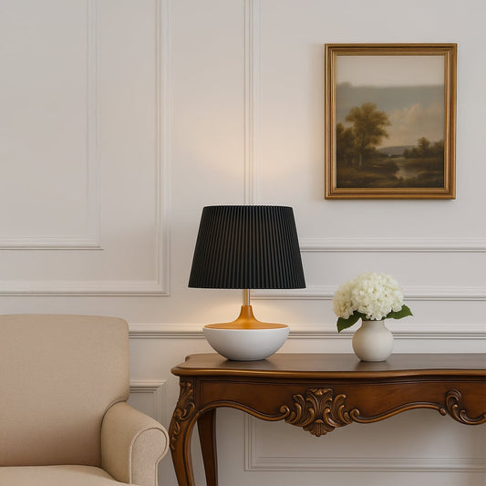 Black pleated table lamp on wooden console with classic wall paneling and floral decor for a sophisticated interior look.