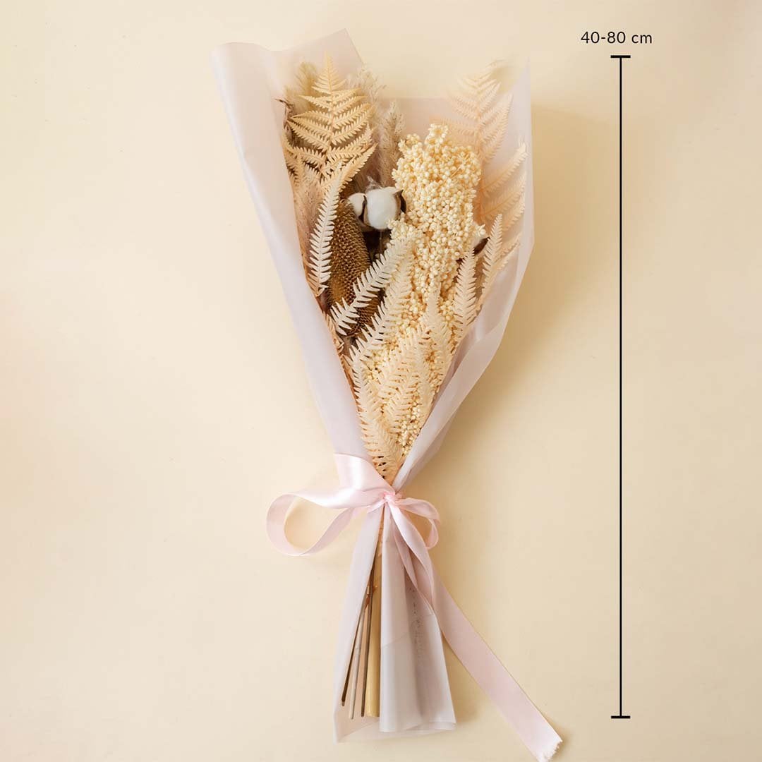 Rustic dried flower bouquet with pampas grass cotton stems preserved amaranthus and fern leaves tied with pink ribbon on plain background.
