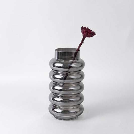 Modern smoky glass vase with single maroon flower styled on a bathroom counter with mirror for elegant minimalist decor.