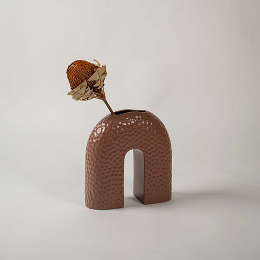Textured brown arched ceramic vase placed on a bright white background highlighting its modern sculptural form.