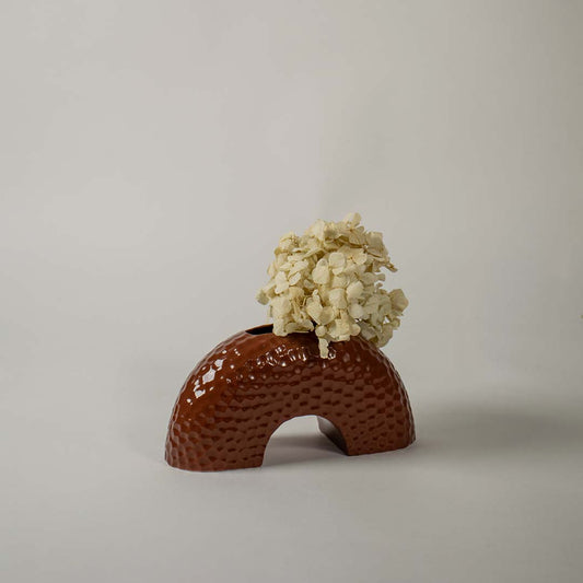 Textured brown arched ceramic vase photographed on a bright white background highlighting its shape and glossy handcrafted finish.