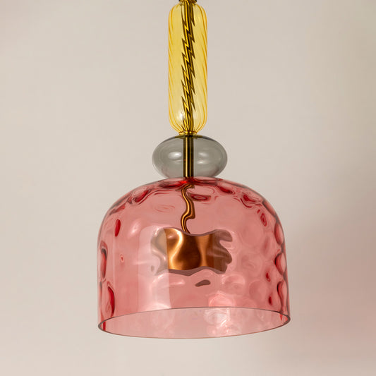 Detailed view of pink textured glass pendant light with brass fittings highlighting artisan design.