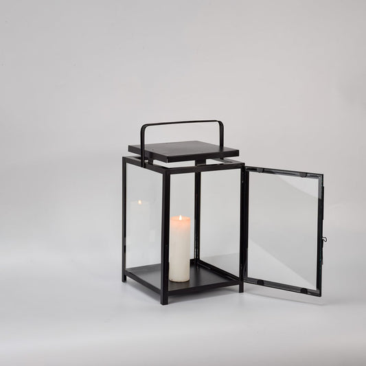Black metal lantern with open glass door and candle holder for elegant tabletop decor styling.