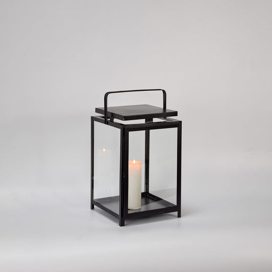 Black metal lantern with clear glass panels and candle holder for modern tabletop decor styling.