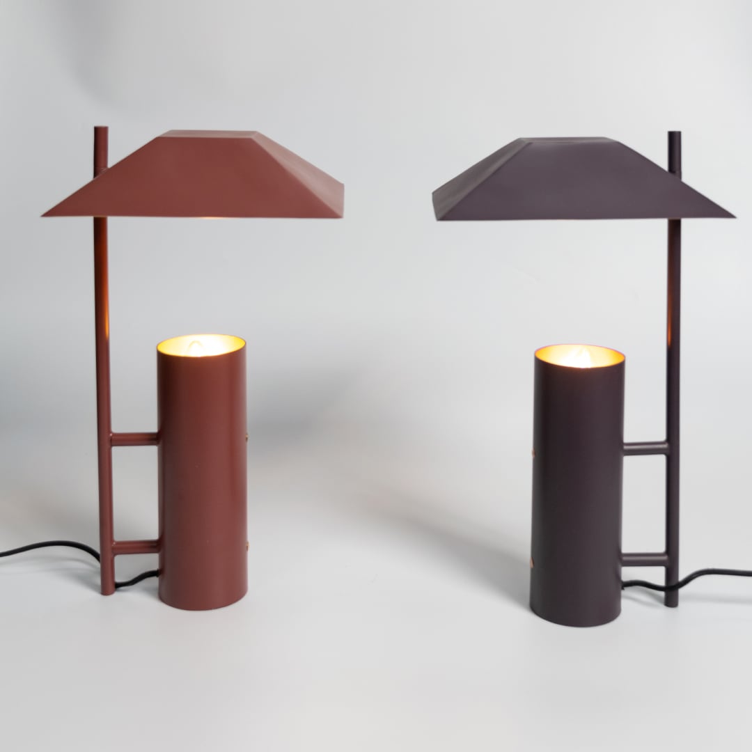 Dark brown metal table lamp with cylindrical base displayed in a styled setup for modern decorative tabletop lighting.