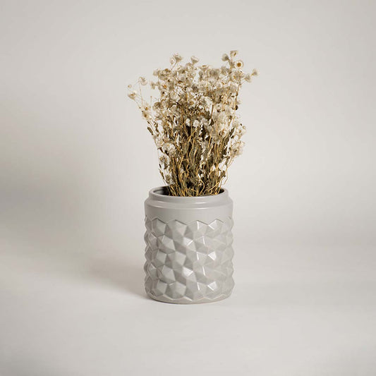 Modern grey ceramic vase with geometric texture displayed in a lifestyle setting enhancing the decor with a subtle contemporary touch.