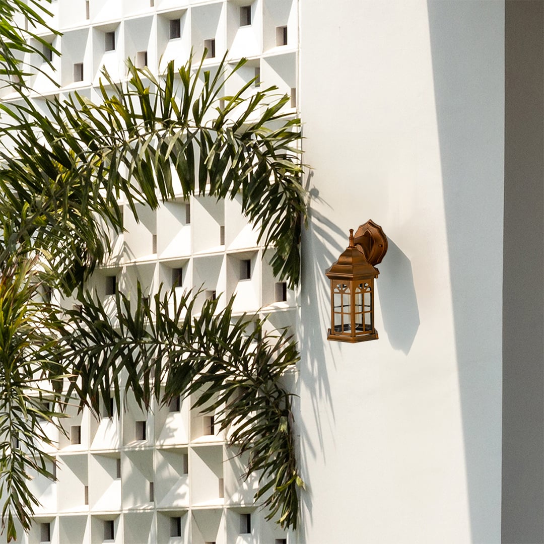 Bronze outdoor lantern with the light off mounted on a bright exterior wall showcasing its classic arched window style glass and elegant vintage lantern design.