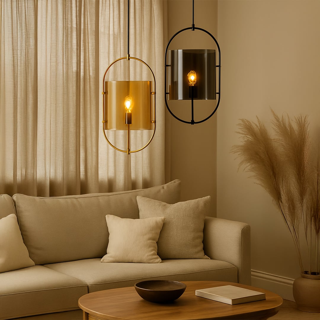 Contemporary pendant lights with oval gold and chrome frames and tinted glass shades softly glowing illuminating a cozy beige living room setup.