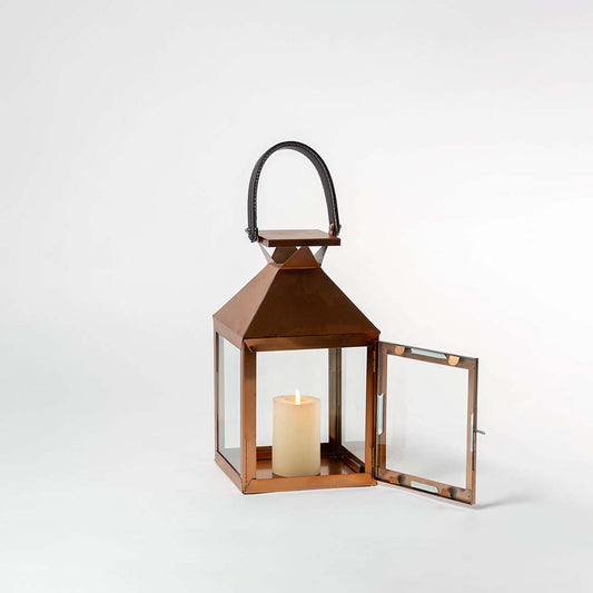Handcrafted copper lantern on white background showing its polished metallic surface transparent glass sides and sturdy black handle — a perfect accent piece for modern and rustic home interiors.