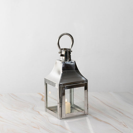 Silver lantern lit shown plain on white background highlighting polished stainless steel frame.