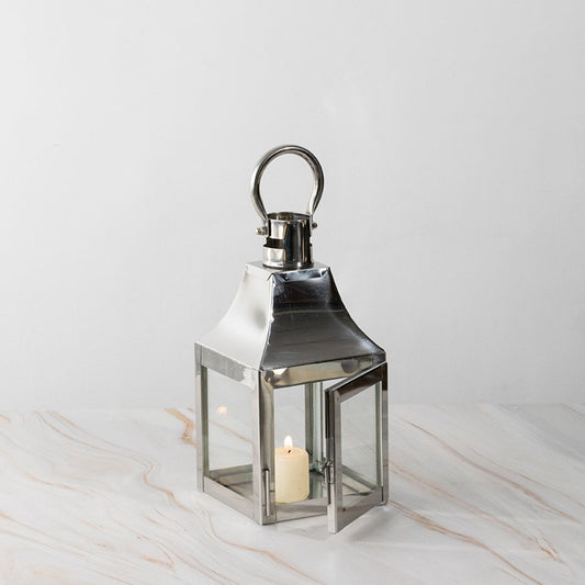 Stainless steel lantern with candle lit displayed on white background for modern home and garden decor.