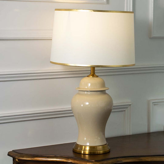 Cream ceramic table lamp with fabric shade and brass base creating refined traditional ambient lighting for interiors.