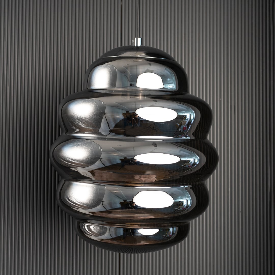 Ripple chrome pendant light turned off against black background showcasing modern craftsmanship and reflective depth.