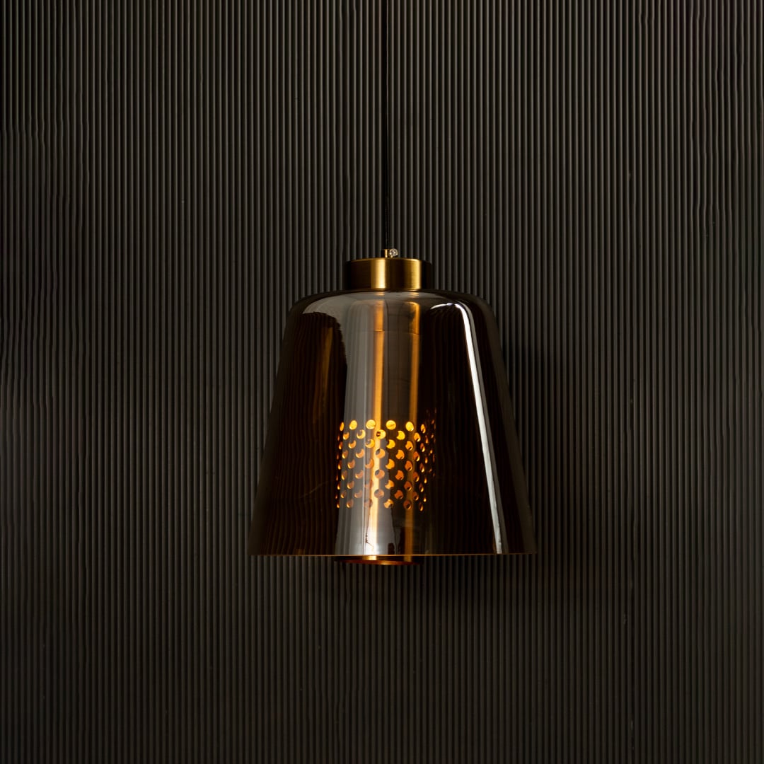 Gold metallic pendant light illuminated on black background creating a rich warm glow and bold reflective look for modern interior lighting.