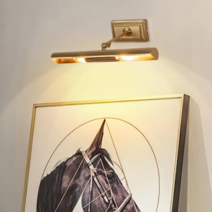Lifestyle closeup of gold metal picture light on a styled wall highlighting warm focused gallery style lighting.