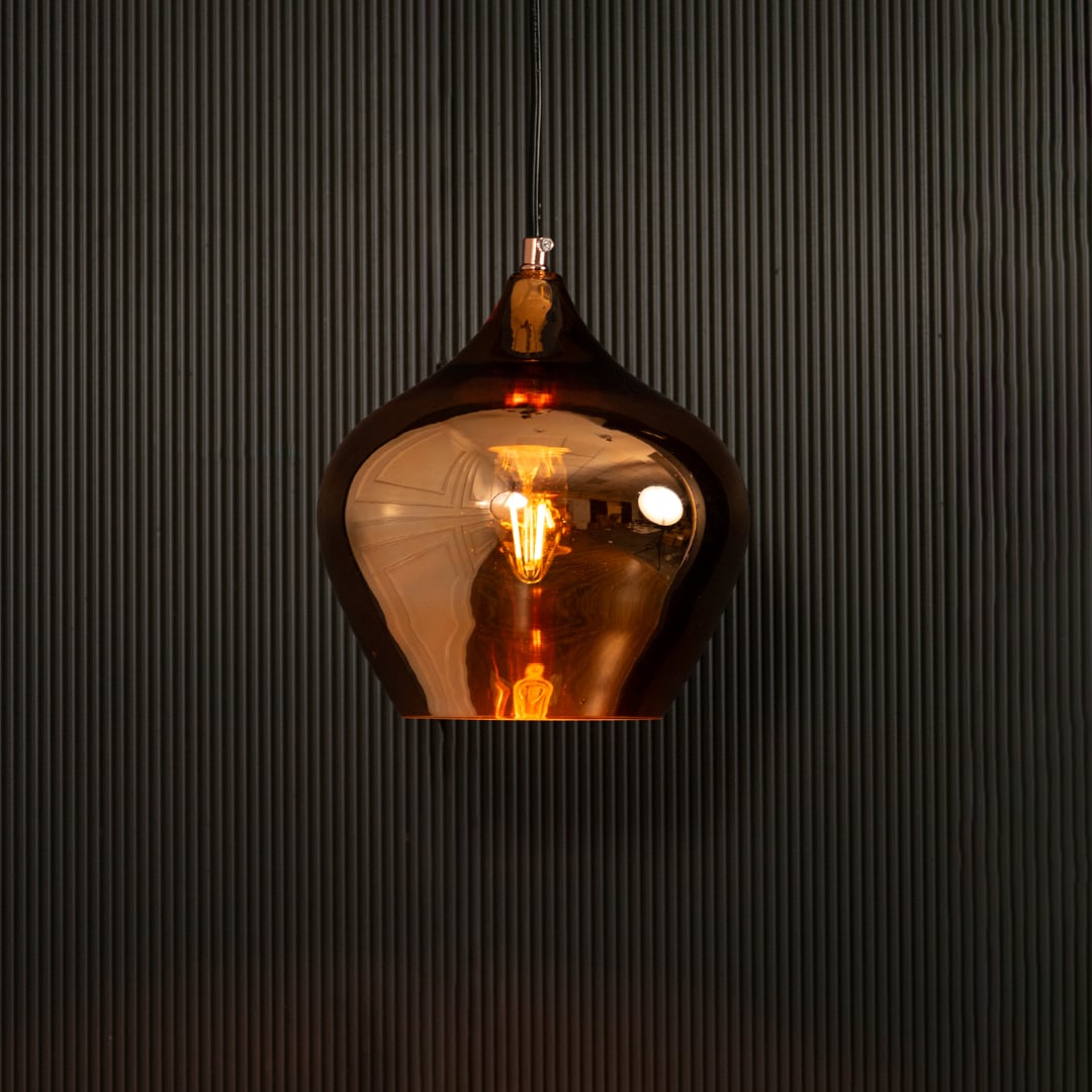 Gold reflective pendant light glowing on black background creating dramatic warm lighting and a bold modern metallic decorative look.