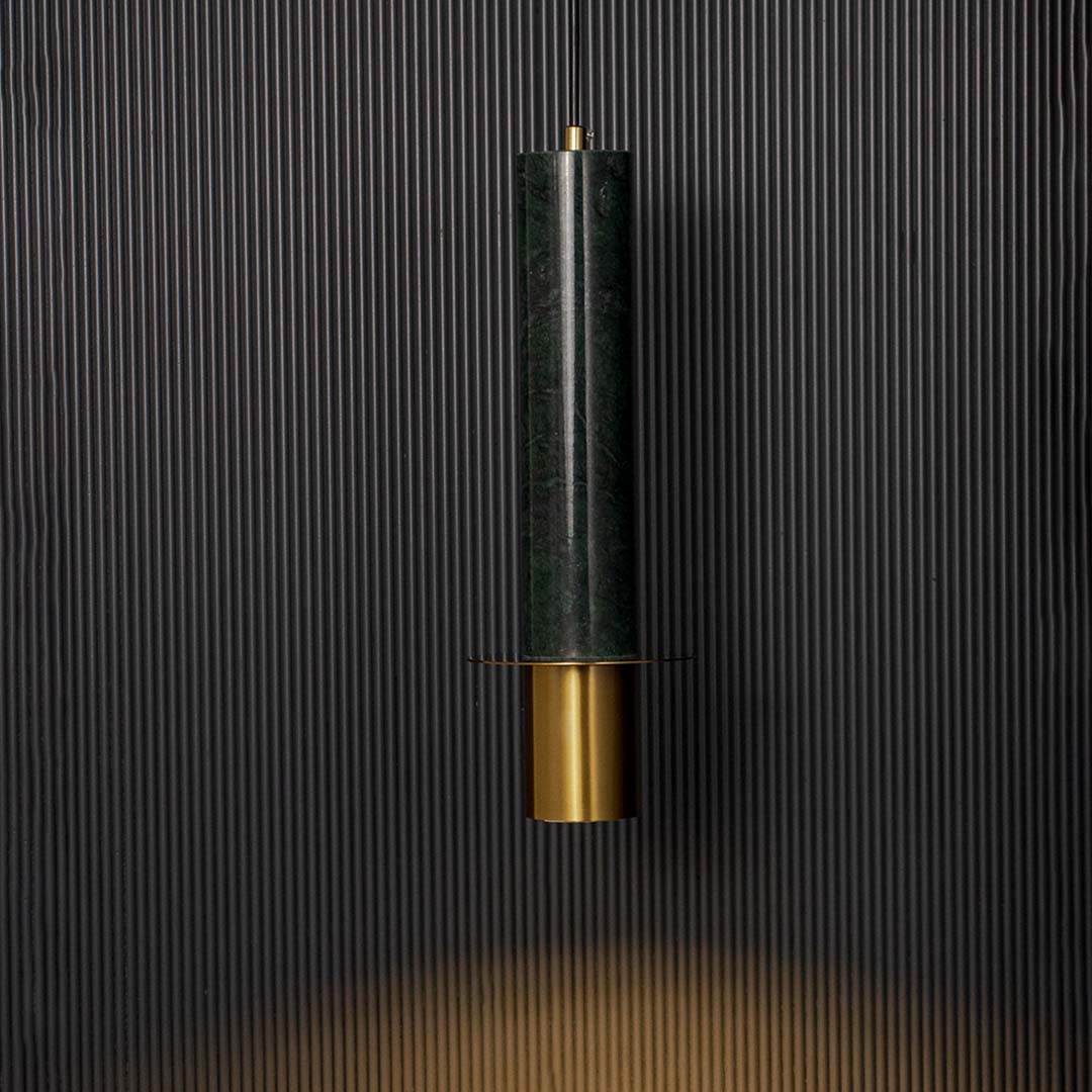 Green marble and brass gold pendant light glowing softly against dark wall creating a warm and sophisticated ambience.
