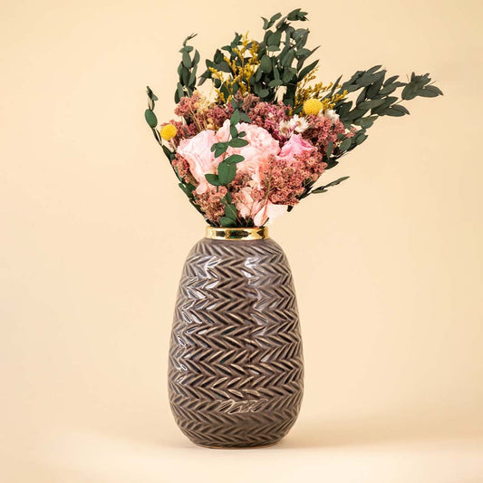 Grey zigzag ceramic vase with gold rim decorated with pink and yellow dried flowers against a beige background for elegant home decor.