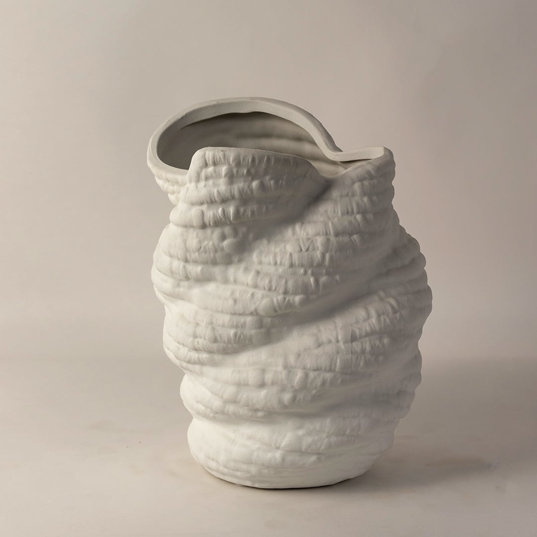 Side angle view of white ceramic sculptural vase with unique textured surface and curved rim ideal for modern home interiors.