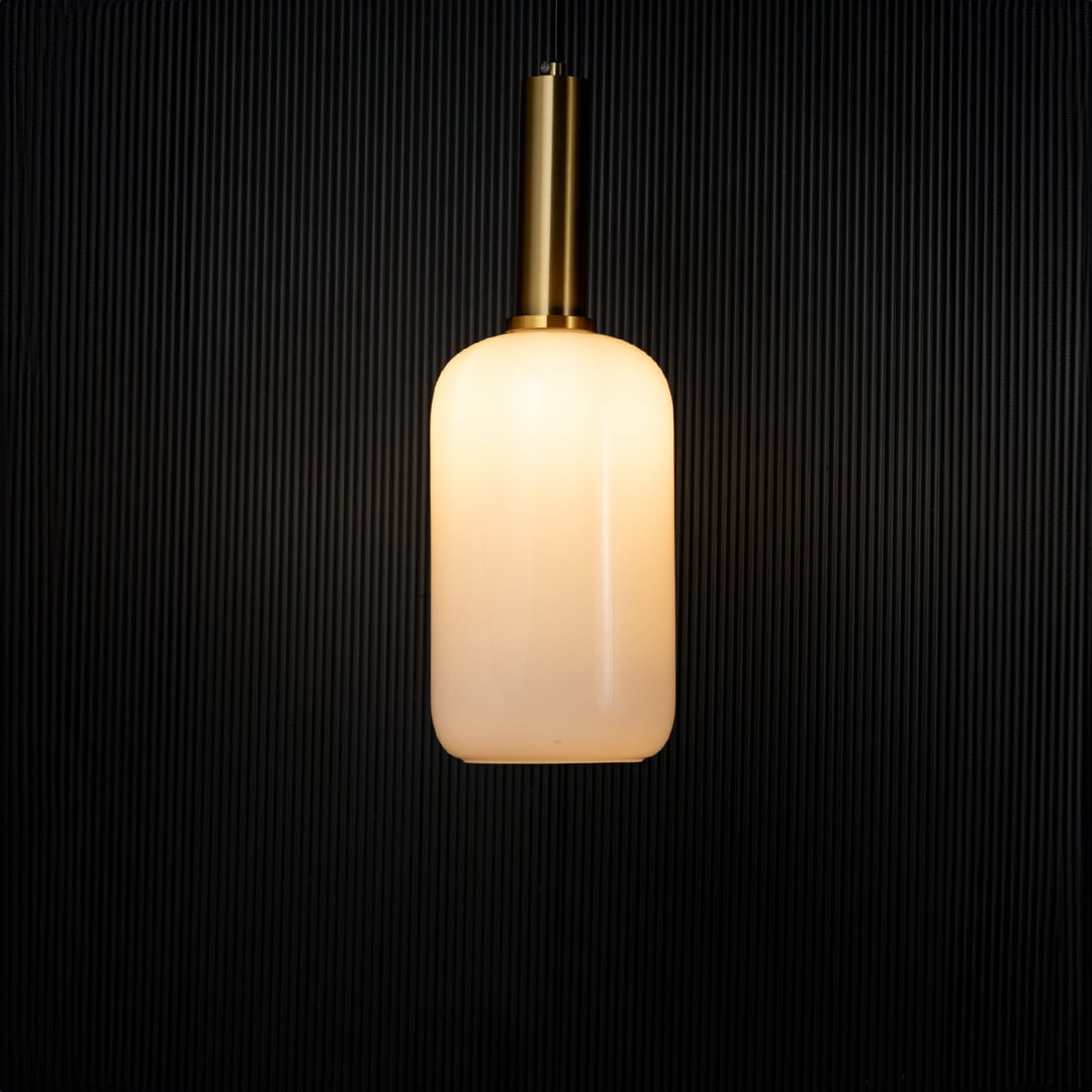 Elegant white glass pendant light turned on with golden holder glowing warmly against black background decor.
