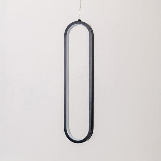 Modern metal elongated loop hanging light in black and white shown switched off on white background for minimal wall decor.