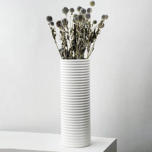 Grey dried globe thistle bouquet preserved flowers styled in tall white ceramic vase lifestyle modern home decor.