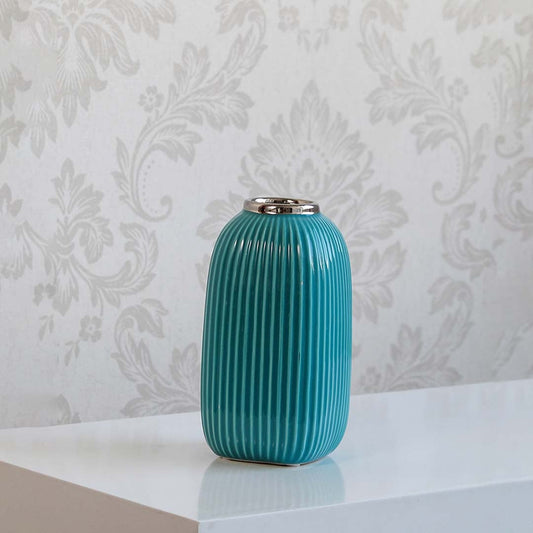 Ribbed blue ceramic vase with glossy finish and silver accent on plain white background.