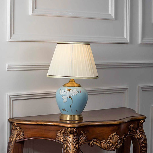Table lamp with light blue ceramic base and white fabric shade on wooden console table stylish lighting for home decor.