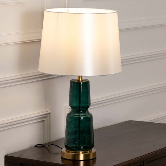 Emerald green ceramic table lamp with fabric shade placed on a wooden console table creating elegant ambient lighting.