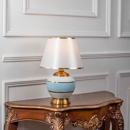 White ceramic table lamp with fabric shade displayed on a carved wooden console table creating elegant traditional lighting.