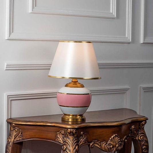 Decorative table lamp with pink ceramic base and white fabric shade on wooden table stylish lighting for bedroom and living room decor.