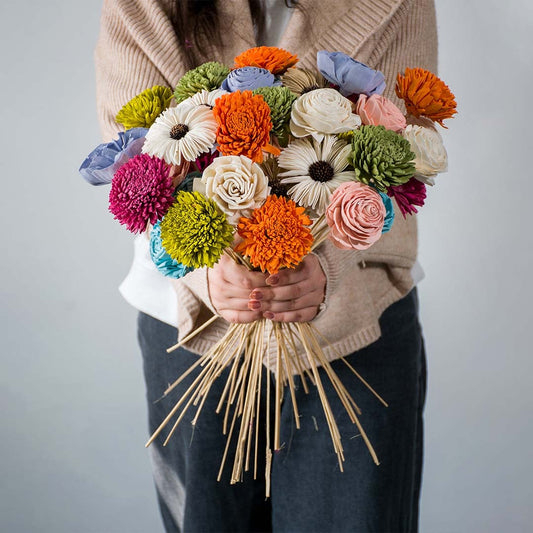 Colorful artificial flower bouquet arranged in blue textured ceramic vase placed on white table for cheerful home decor.