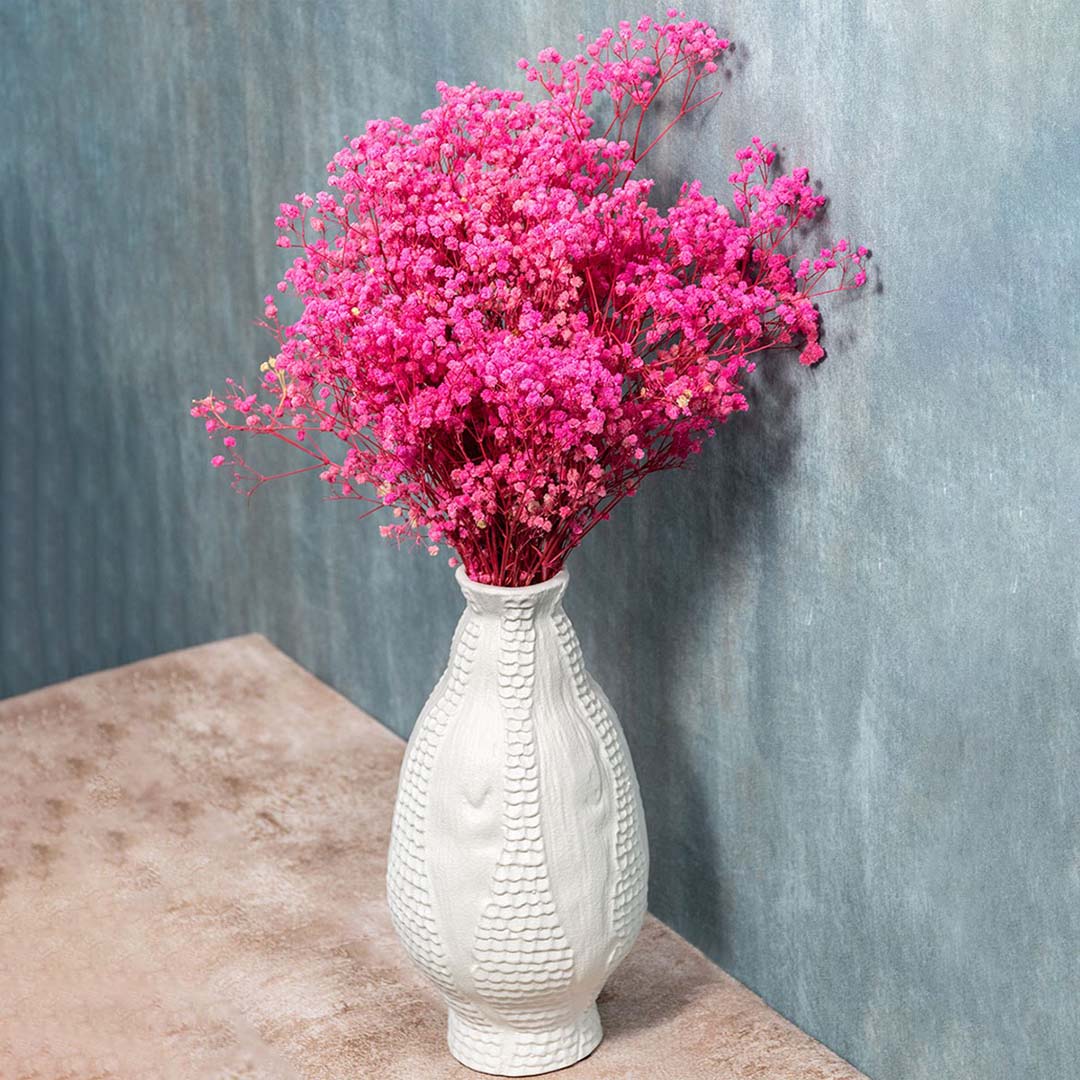 White textured ceramic vase styled with soft pink flowers placed for modern home decor.