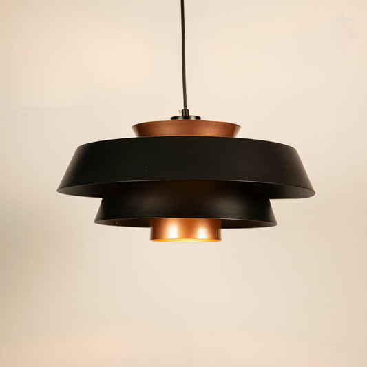 Black and copper metal pendant light glowing softly on white background creating modern industrial ambience for home decor.
