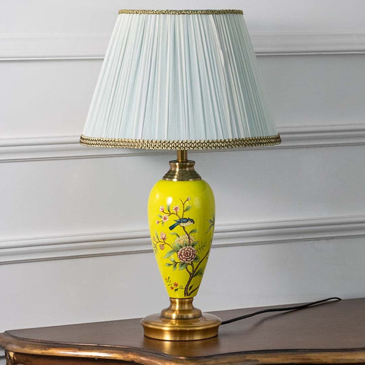 Elegant yellow floral ceramic table lamp with pleated white shade turned off showcasing detailed artwork and golden base finish.