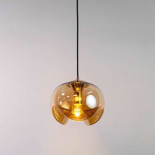 Amber glass and brass metal pendant light with warm illumination for elegant home decor spaces.