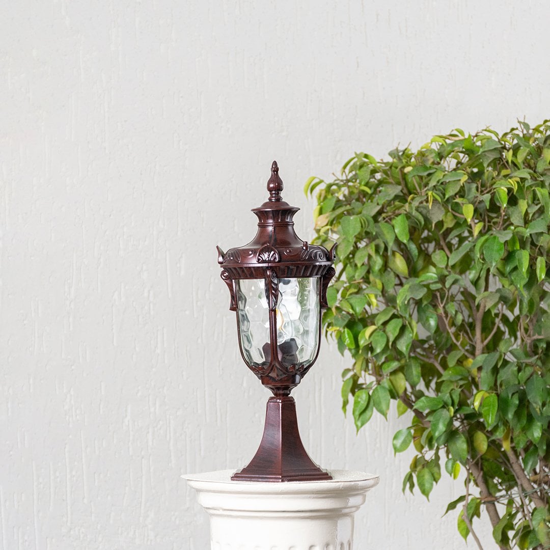 Antique brown pillar light with carved detailing and patterned glass displayed off on white background highlighting classic style.